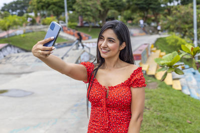 Portrait of young woman photographing with mobile phone