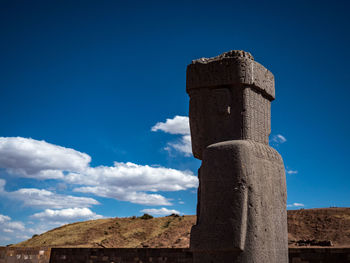 Low angle view of old wooden post against blue sky