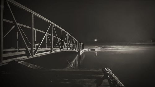 Suspension bridge over river against sky at night