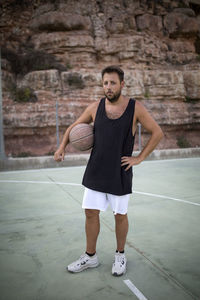 Full length portrait of young man standing against wall