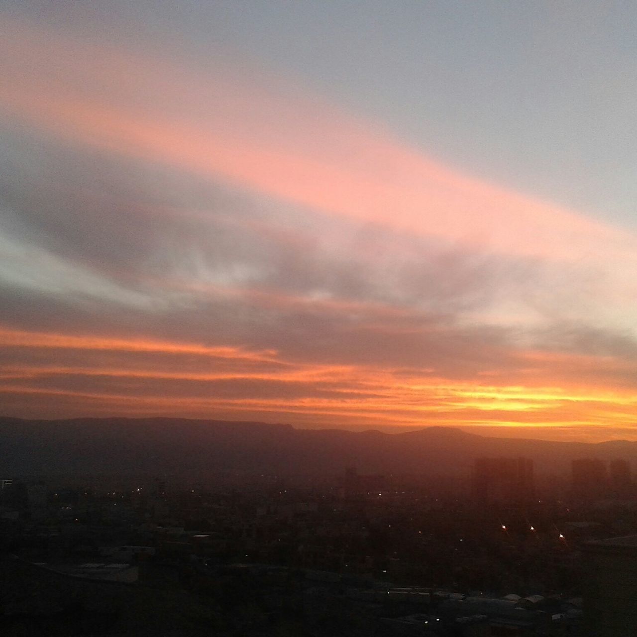 sunset, orange color, cityscape, sky, city, building exterior, cloud - sky, scenics, architecture, built structure, beauty in nature, high angle view, silhouette, crowded, nature, landscape, dramatic sky, tranquil scene, dusk, tranquility