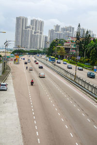 Vehicles on road in city against sky