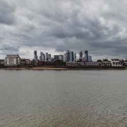 Sea by buildings against sky in city