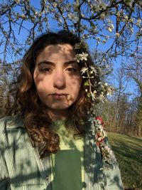 Portrait of young woman standing against trees