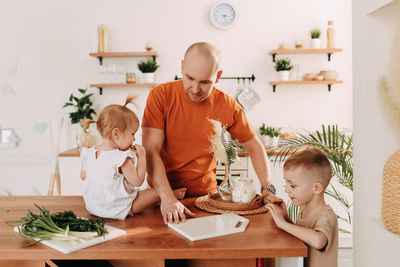 Happy big family of mom dad two kids cooking together and having fun in the kitchen at home