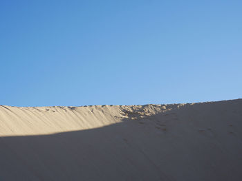 Sand dunes against clear blue sky