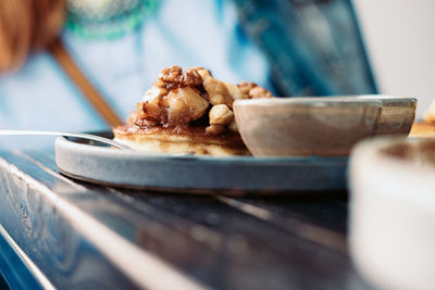 Midsection of person eating belgian waffle with nuts at table