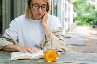 Woman reading book while sitting outdoors