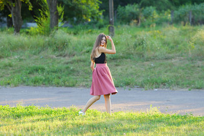 Woman with umbrella standing on grass against trees