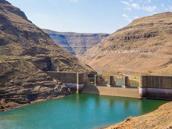 Scenic view of river by dam against sky