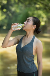 Beautiful woman in sports cloths drinking water in forest