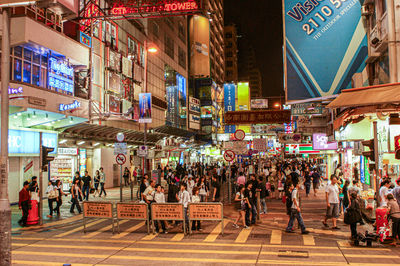 People walking on illuminated street in city at night