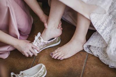 Woman assisting bride in wearing shoes on floor