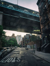 Road sign on bridge in city against sky