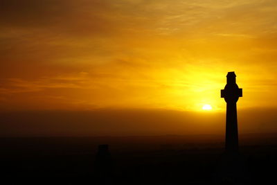 Silhouette cross against sky during sunset