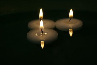 Close-up of illuminated tea light candles in darkroom