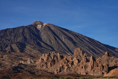 Scenic view of mountains against blue sky