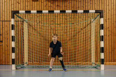 Focused male goalie with disability standing in front of net at sports court