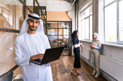 Portrait of woman using digital tablet while standing in office