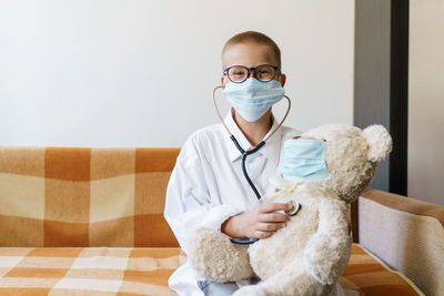 Portrait of boy wearing mask examining stuffed toy