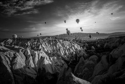 Panoramic shot of hot air balloons on rock formation against sky