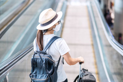 Rear view of woman wearing hat standing by railing