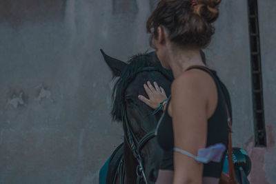 Side view of young woman standing against wall