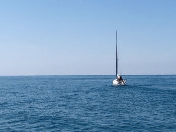 Sailboat sailing on sea against clear sky