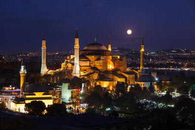 Illuminated mosque against sky at night