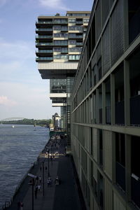 Buildings by footpath in city against sky