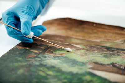 Oil painting cleaning, female conservator removing dirt from an old oil painting