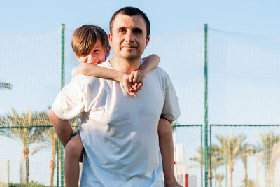 Happy father carrying son on back at sports ground