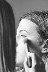 Close-up of woman applying make-up on friend face