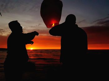 Silhouette man standing against orange sky during sunset