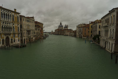 Canal amidst buildings in city against sky