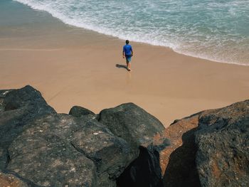 High angle view of man walking on sea shore