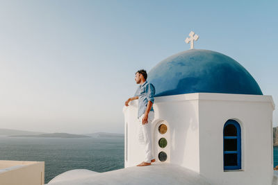 Man standing at chapel by sea at santorini