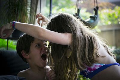 Siblings screaming while playing in lawn