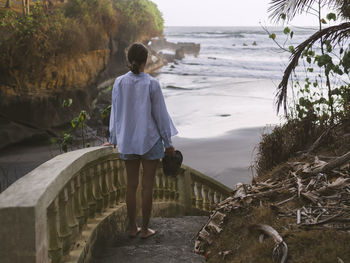 Rear view of woman walking down steps at beach