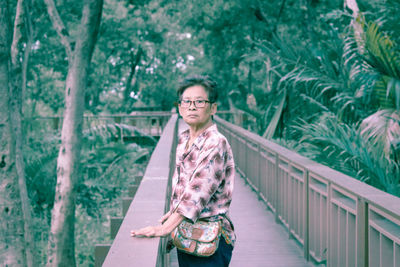 Portrait of smiling woman standing on footbridge