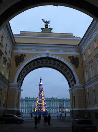 Illuminated christmas tree seen through building arch