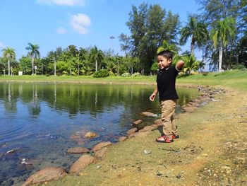 Full length of boy standing by tree against sky