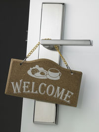 Close-up of welcome text hanging on door handle