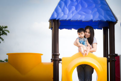 Portrait of woman with baby boy standing on play equipment