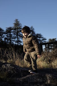 Full length of boy standing on field against sky