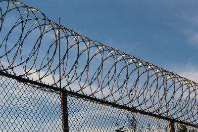 Low angle view of fence against blue sky