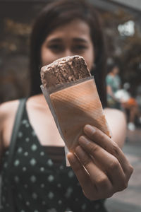 Portrait of woman showing ice cream while standing outdoors