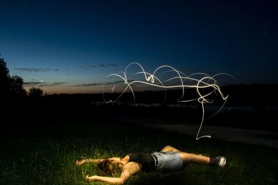 Light painting over woman against sky at night
