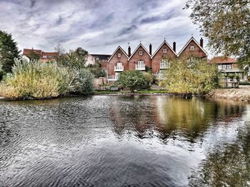 Houses by river and buildings against sky