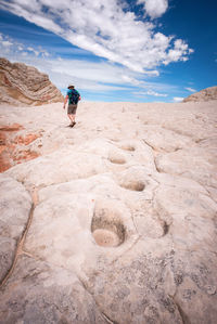 Man walking on rock against sky